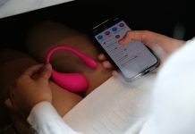 Ultimate Guide to App-Controlled Sex Toys a person holding a cell phone with a pink handle